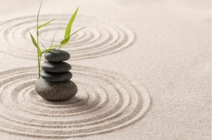 zen stones on sand with green leaf